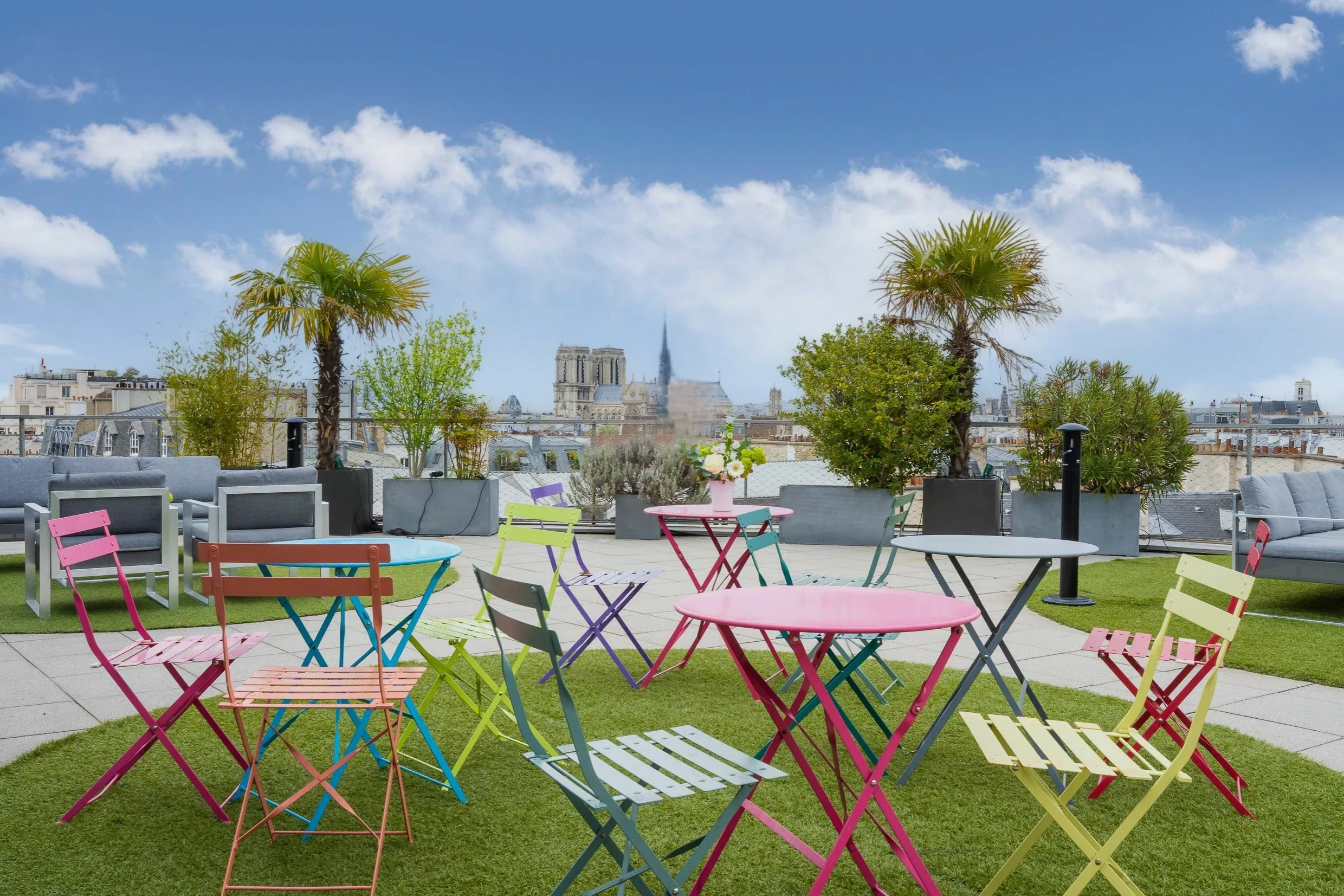 Tables et chaises de bistrot colorées sur le rooftop, face à Notre-Dame de Paris