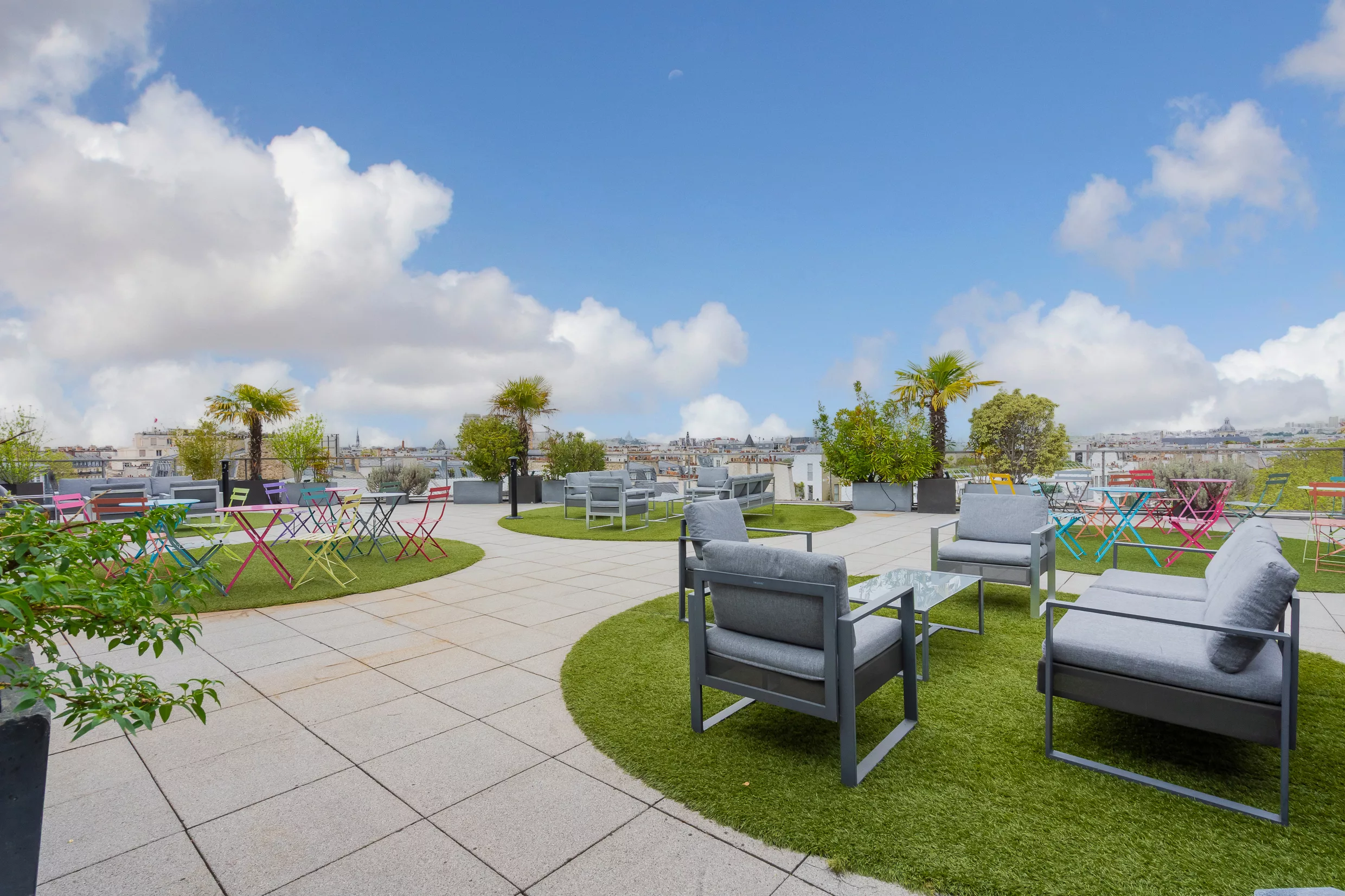 Le rooftop aménagé en îlots : salons et tables bistrot sur gazon